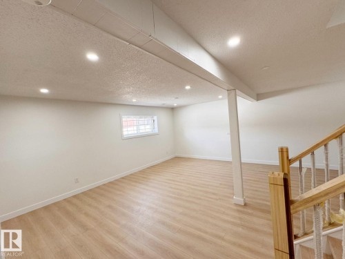 Spacious lower-level room featuring light wood-finish flooring, recessed lighting, and a neutral color palette - 20 Hunt Road, Edmonton, AB - Indoor