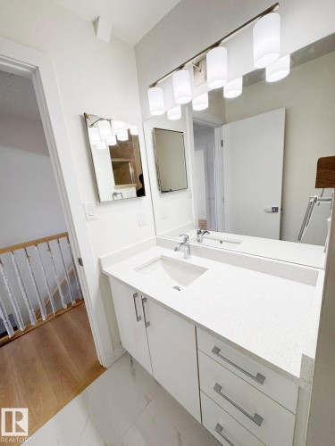 Vanity with white cabinetry and a light-toned countertop, featuring an integrated sink with a chrome faucet - 20 Hunt Road, Edmonton, AB - Indoor Photo Showing Bathroom