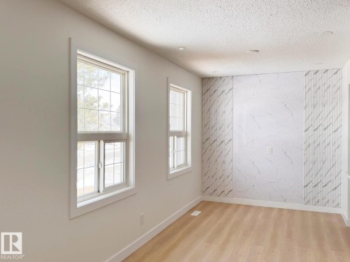 Interior space featuring light wood-finish flooring and a textured accent wall - 20 Hunt Road, Edmonton, AB - Indoor Photo Showing Other Room