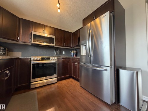 Modern kitchen featuring stainless steel appliances including a refrigerator, range, and microwave - 5204 4 Avenue, Edmonton, AB - Indoor Photo Showing Kitchen With Stainless Steel Kitchen