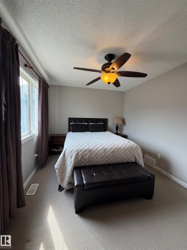 Carpeted room featuring a ceiling fan with integrated lighting, a window with curtains, and neutral wall paint - 5204 4 Avenue, Edmonton, AB - Indoor Photo Showing Bedroom