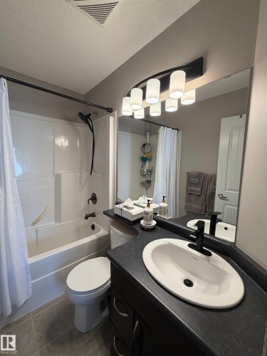 Bathroom featuring a white drop-in sink, dark countertop, and dark wood-finish cabinetry - 5204 4 Avenue, Edmonton, AB - Indoor Photo Showing Bathroom