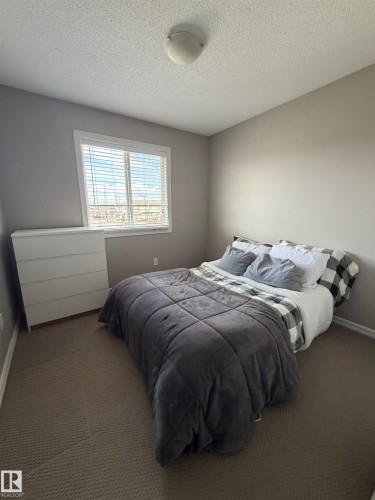 Neutral wall tones, textured ceiling, a flush mount ceiling light fixture, a window with blinds, and carpeting - 5204 4 Avenue, Edmonton, AB - Indoor Photo Showing Bedroom
