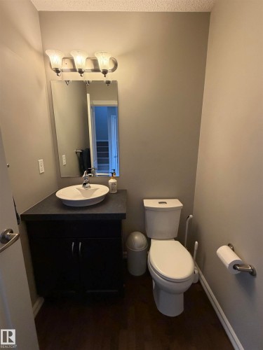 Powder room featuring a dark wood-finish vanity with a vessel sink, a dark countertop, and a wall-mounted light fixture - 5204 4 Avenue, Edmonton, AB - Indoor Photo Showing Bathroom