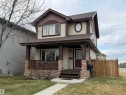 Two-story residence featuring a covered front porch with stone veneer columns, a dark wood entry door with decorative glass, and contrasting light siding with dark trim - 5204 4 Avenue, Edmonton, AB  - Outdoor With Deck Patio Veranda 