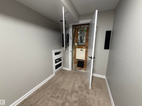 Carpeted flooring with light gray walls, featuring a built-in tower for X-box, electronic system, white baseboards. - 5204 4 Avenue, Edmonton, AB - Indoor Photo Showing Other Room