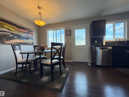 Dining area featuring wood-finish flooring, a contemporary pendant light fixture, and a window with natural light - 5204 4 Avenue, Edmonton, AB - Indoor Photo Showing Dining Room