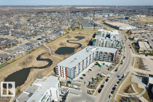 Aerial perspective of a multi-unit residential building with integrated parking, bordering a public road - 318 1316 Windermere Way, Edmonton, AB -  With View