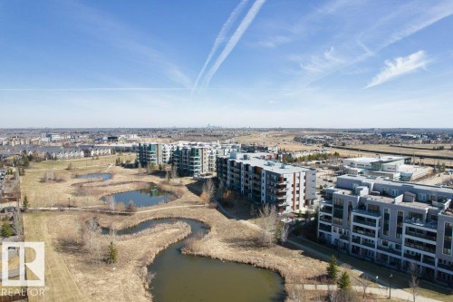 Aerial perspective showcasing multiple residential buildings and a naturalized park area - 318 1316 Windermere Way, Edmonton, AB - Outdoor With View