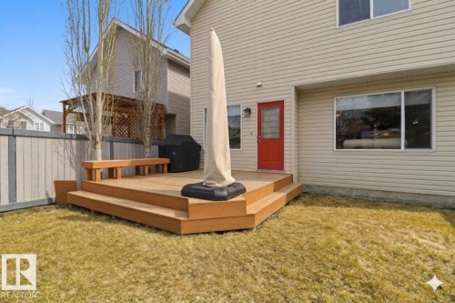 Expansive backyard featuring a multi-level wooden deck with integrated bench seating, providing outdoor access from a red exterior door - 8311 11 Avenue, Edmonton, AB - Outdoor With Deck Patio Veranda With Exterior