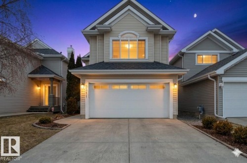 Exterior featuring a two-story design with light-toned siding, an attached garage, a paved driveway, and a covered entry porch - 8311 11 Avenue, Edmonton, AB - Outdoor