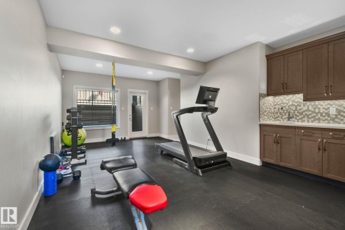 Dedicated exercise space featuring black rubber flooring, recessed lighting, and a built-in wet bar - 67 Enchanted Way Nw, St. Albert, AB - Indoor Photo Showing Gym Room