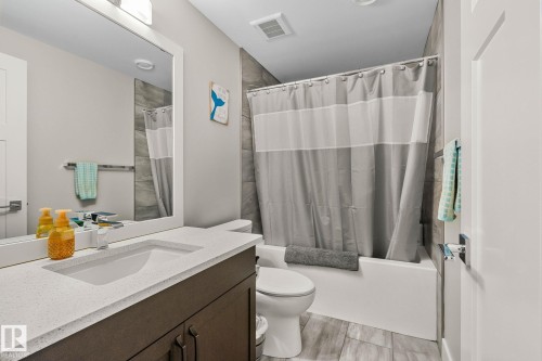 Bathroom featuring a white vanity with an integrated sink, a light-colored countertop, and a dark wood-finish cabinet - 67 Enchanted Way Nw, St. Albert, AB - Indoor Photo Showing Bathroom