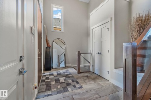 Entryway featuring tile flooring, a high ceiling, and a prominent staircase with wood newel posts and glass panels - 67 Enchanted Way Nw, St. Albert, AB - Indoor Photo Showing Other Room
