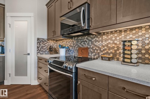 Kitchen featuring warm wood-finish cabinetry and a complementary hexagonal tile backsplash - 67 Enchanted Way Nw, St. Albert, AB - Indoor Photo Showing Kitchen