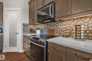 Kitchen featuring warm wood-finish cabinetry and a complementary hexagonal tile backsplash - 67 Enchanted Way Nw, St. Albert, AB  - Indoor Photo Showing Kitchen 