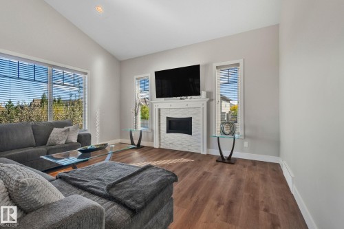 Spacious living area featuring high vaulted ceilings, wood-finish flooring, and a fireplace with a tiled surround - 67 Enchanted Way Nw, St. Albert, AB - Indoor Photo Showing Living Room With Fireplace