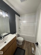 Bathroom featuring a wood-finish vanity with an integrated white sink, chrome faucet, and a large wall mirror - 