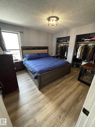 Bedroom featuring wood-finish flooring, two open closet spaces with hanging storage, and a ceiling-mounted light fixture - 5108 58 Avenue, Elk Point, AB - Indoor Photo Showing Bedroom