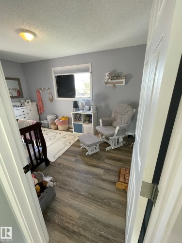Bedroom featuring wood-finish flooring, a window with natural light, and a built-in overhead light fixture - 5108 58 Avenue, Elk Point, AB - Indoor