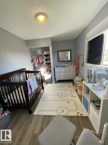 Room featuring wood-finish flooring, a built-in closet with shelving, a window with blinds, and a flush-mount ceiling light fixture - 5108 58 Avenue, Elk Point, AB - Indoor Photo Showing Bedroom
