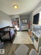 Room featuring wood-finish flooring, a built-in closet with shelving, a window with blinds, and a flush-mount ceiling light fixture - 