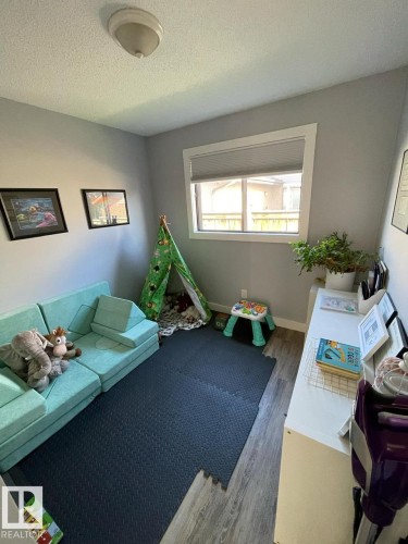 Room featuring wood-finish flooring, light gray wall paint, and a window with a white frame and roller blind - 5108 58 Avenue, Elk Point, AB - Indoor