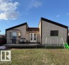 Stucco exterior with a multi-level roofline, featuring a rear wood deck, double glass panel doors, and a bay window - 5108 58 Avenue, Elk Point, AB  - Outdoor With Deck Patio Veranda 