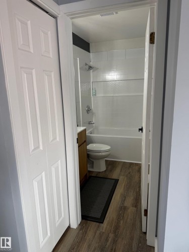 Bathroom featuring wood-finish flooring, a white porcelain bathtub, and white subway tile surround - 5108 58 Avenue, Elk Point, AB - Indoor Photo Showing Bathroom