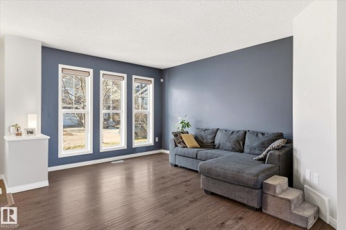 Spacious room featuring rich wood-finish flooring and three large windows with roller shades - 7114 22 Avenue, Edmonton, AB - Indoor Photo Showing Living Room