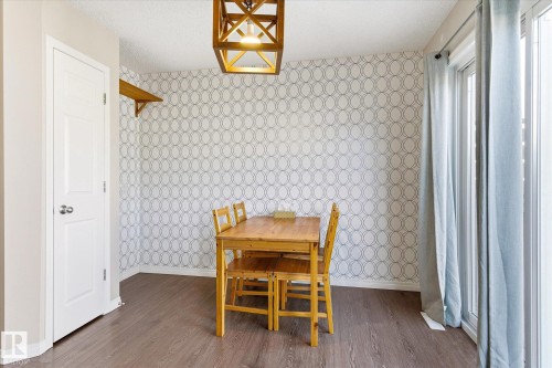 Dining area with geometric pattern wallpaper, wood-finish flooring, and a large sliding glass door - 7114 22 Avenue, Edmonton, AB - Indoor Photo Showing Other Room