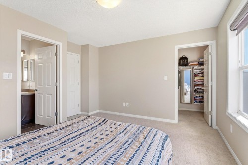 Bedroom featuring neutral wall paint, carpet flooring, a window with a roller shade, and an open doorway to a closet with shelving - 7114 22 Avenue, Edmonton, AB - Indoor