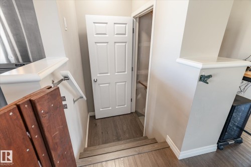 Staircase entry featuring wood-finish flooring, white baseboards, and a six-panel interior door - 7114 22 Avenue, Edmonton, AB - Indoor Photo Showing Other Room