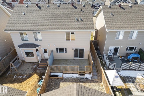 Rear exterior featuring a large elevated deck with wood railing, bay window, and sliding glass door access - 7114 22 Avenue, Edmonton, AB - Outdoor