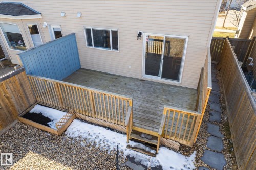 Rear wooden deck with staircase access and slatted railing, featuring an adjacent built-in planter box - 7114 22 Avenue, Edmonton, AB - Outdoor With Exterior