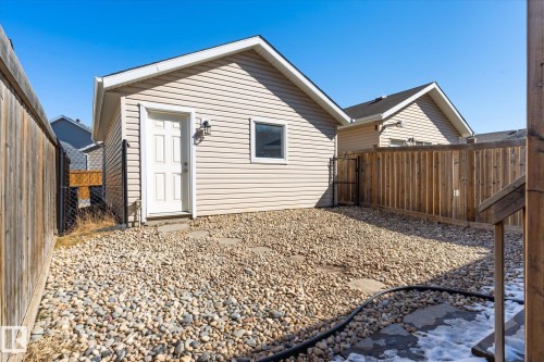 Detached accessory dwelling with beige horizontal siding, a white paneled entry door, and an exterior light fixture - 7114 22 Avenue, Edmonton, AB - Outdoor With Exterior