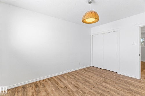 Interior room featuring wood-look flooring, white walls, and a light fixture with a woven shade - 12823 81 Street, Edmonton, AB - Indoor Photo Showing Other Room