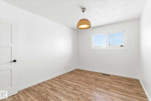 Room featuring light wood-style flooring, a window providing natural light, and a modern ceiling light fixture - 12823 81 Street, Edmonton, AB - Indoor Photo Showing Other Room