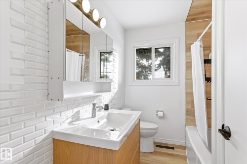 The bathroom features a modern vanity with a white rectangular sink, a mirrored medicine cabinet with integrated lighting, and a white subway tile backsplash - 12823 81 Street, Edmonton, AB - Indoor Photo Showing Bathroom