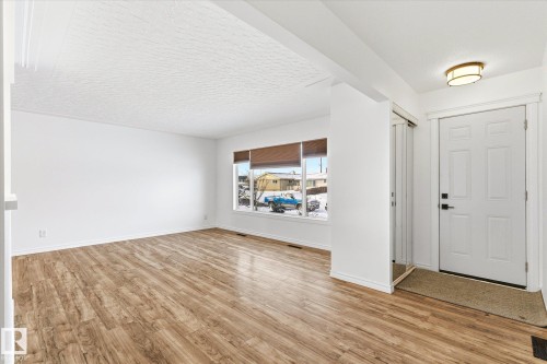 This inviting entry area features durable wood-look flooring, a white front door, and a modern ceiling light fixture - 12823 81 Street, Edmonton, AB - Indoor