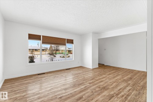 Living area featuring light wood-style flooring, white walls, and a large window with brown blinds - 12823 81 Street, Edmonton, AB - Indoor Photo Showing Living Room