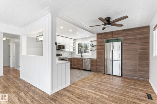 The kitchen features a stainless steel refrigerator, dishwasher, and microwave, with a white and wood-toned cabinet design - 12823 81 Street, Edmonton, AB - Indoor Photo Showing Kitchen