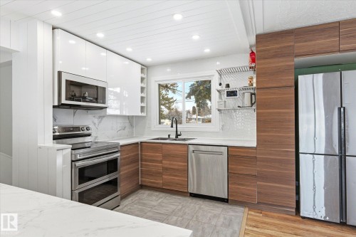 The kitchen features a window above the sink, stainless steel appliances, and a combination of white and wood-toned cabinetry - 12823 81 Street, Edmonton, AB - Indoor Photo Showing Kitchen With Double Sink With Upgraded Kitchen