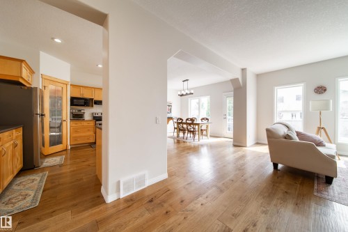 Wood-finish flooring throughout, with a kitchen featuring wood cabinetry and stainless steel appliances - 1205 Ormsby Lane, Edmonton, AB - Indoor