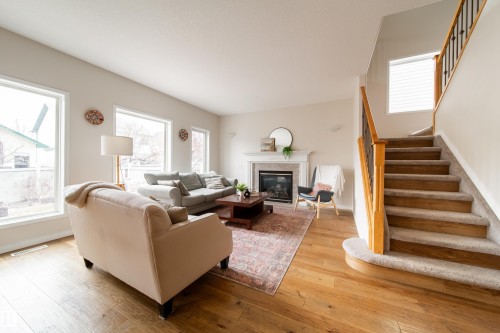 Hardwood-finish flooring throughout the main level - 1205 Ormsby Lane, Edmonton, AB - Indoor Photo Showing Living Room With Fireplace