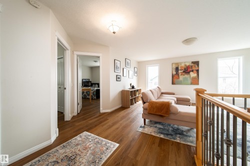 Upper-level landing featuring wood-finish flooring, light-toned walls, and a wood handrail with decorative metal balusters - 1205 Ormsby Lane, Edmonton, AB - Indoor