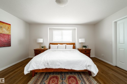 Light-filled interior featuring a window with blinds, wood-finish flooring, white baseboards, and a sliding door - 1205 Ormsby Lane, Edmonton, AB - Indoor Photo Showing Bedroom