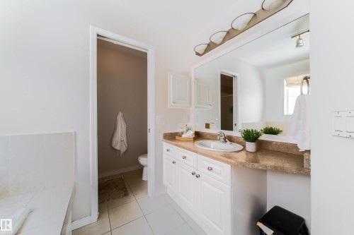 Bathroom featuring a white vanity with multiple storage cabinets, a built-in sink, and a light-colored countertop - 1205 Ormsby Lane, Edmonton, AB - Indoor Photo Showing Bathroom
