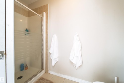 Shower enclosure with frosted glass door, tile surround, and neutral wall finish - 1205 Ormsby Lane, Edmonton, AB - Indoor Photo Showing Bathroom