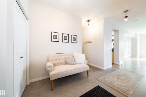 Entryway featuring neutral wall tones, square tile flooring, a built-in closet with bifold doors, and modern flush-mount lighting fixtures - 1205 Ormsby Lane, Edmonton, AB - Indoor